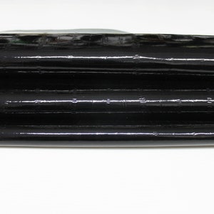 May include: Black leather with a textured, crocodile-like pattern. The leather is folded in thirds.