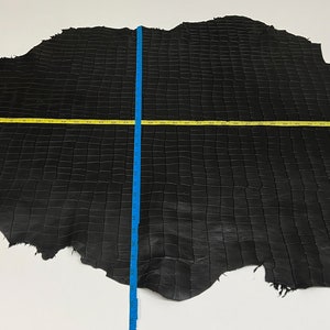 May include: Black crocodile leather hide with a square pattern. The hide measures approximately 70 inches in length and 40 inches in width.
