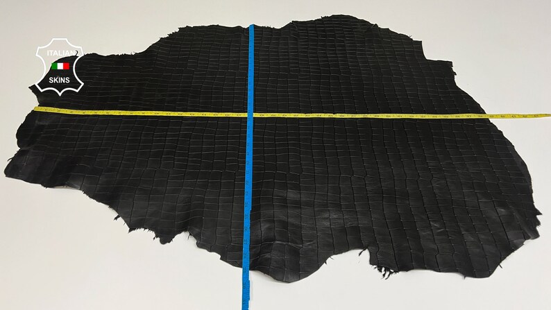 May include: Black crocodile leather hide with a square pattern. The hide measures approximately 70 inches in length and 40 inches in width.
