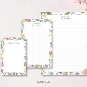 May include: Three rectangular notepads of varying sizes featuring a watercolor floral border with green leaves, blue berries, and pink and white flowers. Each notepad includes the printed text A note from My text Here at the top.