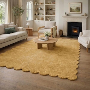 Könnte beinhalten: Ein senfgelber Teppich mit gewelltem Rand in einem Wohnzimmer. Der Teppich liegt auf einem Holzboden, umgeben von einem Sofa, Stühlen und einem Couchtisch. Der Raum hat einen Kamin und große Fenster.