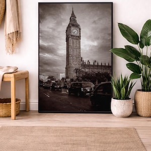 Könnte beinhalten: Schwarz-Weiß-Druck des Elizabeth Tower, auch bekannt als Big Ben, in London. Das Bild zeigt den berühmten Uhrturm vor einem bewölkten Himmel, mit Autos auf der Straße. Der Druck wird in einem Raum mit Pflanzen und einem Teppich ausgestellt.