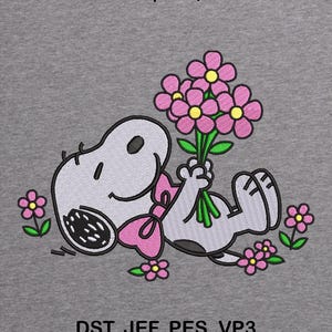 May include: Embroidered design of a cartoon dog with a pink bow, holding a bouquet of pink flowers with yellow centres. The design includes the text "2 SIZES | 5X7, 6X10" and "DST, JEF, PES, VP3". The background is grey.
