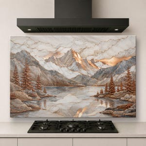 May include: A rectangular kitchen backsplash panel featuring a landscape print of snow-capped mountains, a calm lake, and evergreen trees. The artwork displays a marble-like texture with a color palette of white, gray, and metallic copper tones.