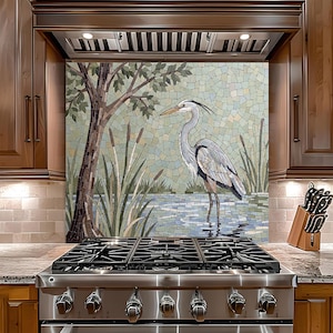 May include: A mosaic backsplash depicting a heron in water, with reeds and a tree on the left. The mosaic uses small, irregular tiles in blue, green, and brown. The kitchen features a stainless steel stove.