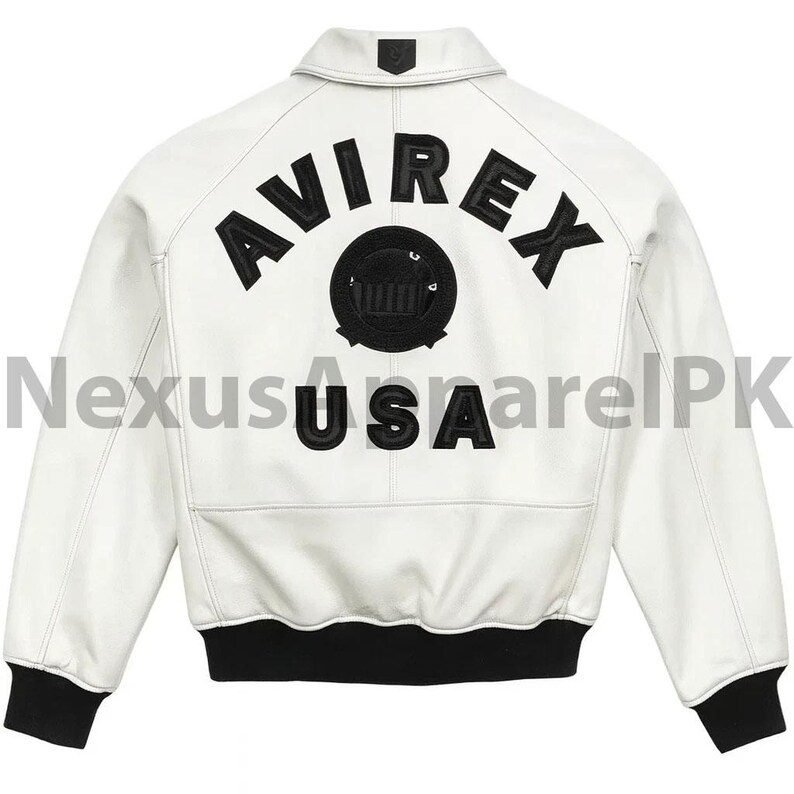 Puede incluir: Chaqueta de cuero blanca con pu&ntilde;os y dobladillo negros. La parte trasera presenta la palabra "AVIREX" en letras negras sobre un emblema circular y la palabra "USA".