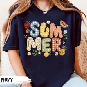 Puede incluir: Camiseta azul marino con la palabra "SUMMER" en letras coloridas y estampadas. El diseño incluye fresas, una rodaja de sandía, margaritas, un limón y una piña. La palabra "NAVY" está impresa en la parte inferior.