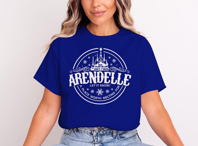 May include: Royal blue t-shirt featuring a white circular graphic with the word "ARENDELLE" above "LET IT SNOW!" and "A PLACE WORTH MELTING FOR". The graphic includes a castle and snowflakes.
