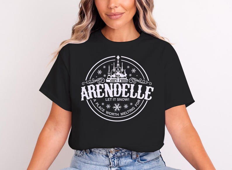 May include: Black t-shirt with a white circular graphic featuring the word "Arendelle" and a castle illustration. The text "Let it snow!" and "A place worth melting for" are also included in the design.
