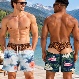 May include: Two pairs of swim shorts featuring a leopard print waistband with a drawstring. The left pair is light blue with sailboats and hibiscus flowers. The right pair is dark green with pink flamingos and white tropical flowers.