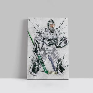 Peut inclure: Impression sur toile d'un gardien de but de hockey sur glace en uniforme blanc et gris avec l'inscription "Michigan State" sur la poitrine. Le gardien tient une crosse de hockey verte et noire. Le fond présente des éclaboussures de peinture grises et noires.