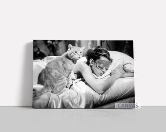 May include: Monochrome canvas print showing a woman in bed wearing a sleep mask, with a cat beside her. The cat is ginger and white. The woman is holding a small object. The word "CANVAS" is visible.