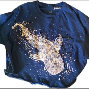 Puede incluir: Camiseta azul marino con un diseño de tiburón ballena de color claro. El diseño incluye un bolsillo y está adornado con salpicaduras de pintura de color claro. La palabra "forever" está escrita en el cuello.