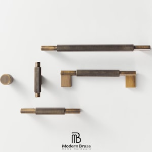 May include: A collection of brass hardware, including cabinet pulls and a knob, against a white background. The hardware features a textured, knurled design on the central bar and a warm, antique brass finish. The Modern Brass logo is visible at the bottom.