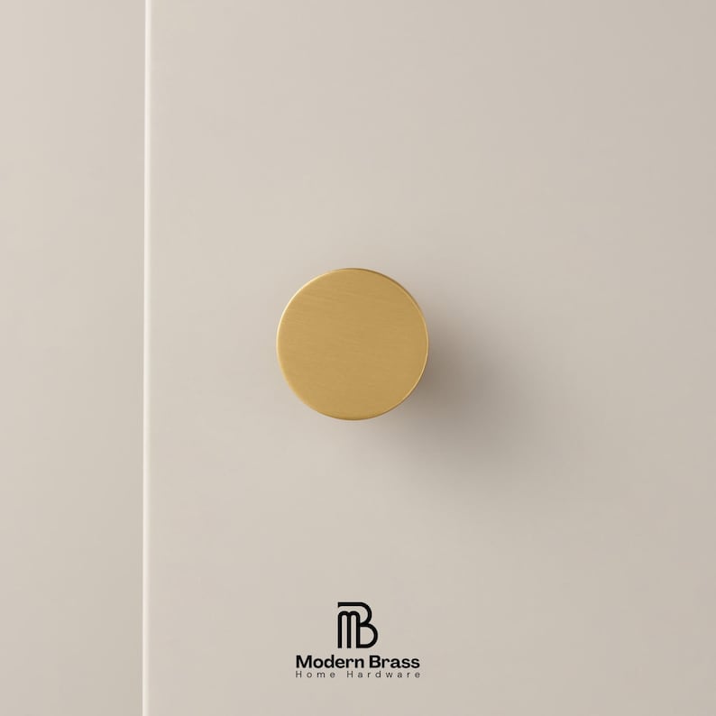 Brushed brass knob set displayed on a white architectural block to show various diameters.