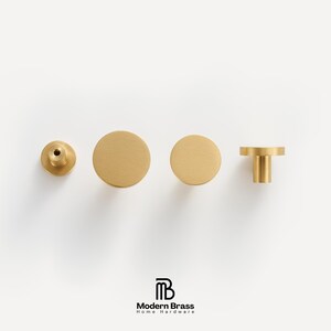 Minimalist round furniture pulls in brushed brass, illustrating the underside mounting hole and stem.