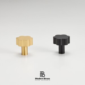 An architectural antique brass hardware set including long appliance pulls and small drawer knobs.