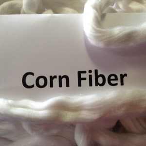 May include: White corn fiber, a natural material, is shown in a pile. A white label with the text "Corn Fiber" is visible in the image.