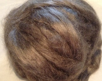 May include: A close-up of a clump of brown wool fiber. The wool is soft and fluffy, and it appears to be natural.