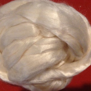 May include: A close-up of a ball of white silk fiber. The fiber is soft and fluffy, and it is perfect for spinning or weaving.