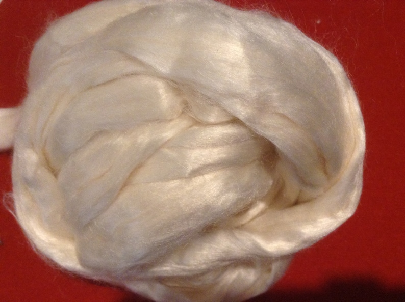 May include: A close-up of a ball of white silk fiber. The fiber is soft and fluffy, and it is perfect for spinning or weaving.