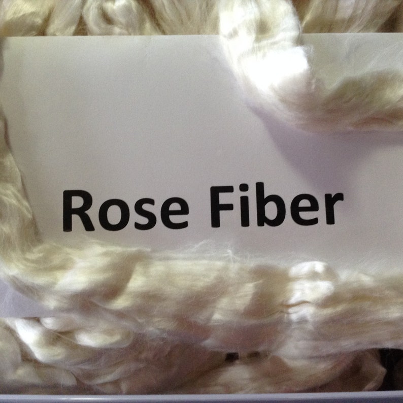 May include: Close-up of a pile of white, fluffy rose fiber. The text "Rose Fiber" is printed on a white label.