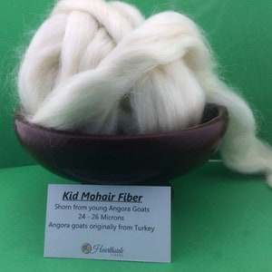 May include: White kid mohair fiber in a brown bowl, with a white label that reads "Kid Mohair Fiber Shorn from young Angora Goats 24-26 Microns Angora goats originally from Turkey Hearthside Fibers".