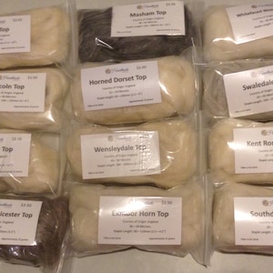 May include: Twelve clear plastic bags each containing a different type of wool top. Each bag has a label with the name of the wool, the country of origin, the staple length, and the micron count. The wool tops are in various shades of white, gray, and brown.