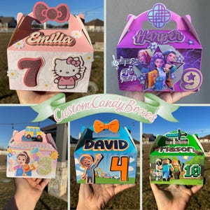 May include: A collection of custom candy boxes in various colors, each personalized with names and numbers. Designs include a Hello Kitty theme, a musical theme, a cartoon character theme, and a Minecraft theme. The boxes are decorated with bows and other embellishments.