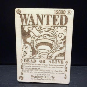 May include: Wooden card with the text "WANTED" and an illustration of a character. The card also features the text "DEAD OR ALIVE" and "Monkey.D.Luffy". The card is a light brown color.