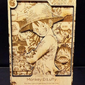 Puede incluir: Tarjeta coleccionable de madera con una imagen grabada con láser de Monkey D. Luffy de One Piece. La tarjeta tiene un efecto 3D, con el personaje en primer plano y paneles de cómic en el fondo. El texto "Monkey D. Luffy" es visible.