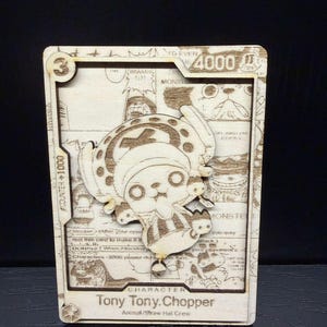 Puede incluir: Tarjeta de madera cortada con láser con Tony Tony Chopper de One Piece. La tarjeta tiene un efecto 3D, con el personaje superpuesto a un cómic. El texto incluye "Tony Tony. Chopper" y "Animal/Straw Hat Crew." Mide unos 10 cm de alto.