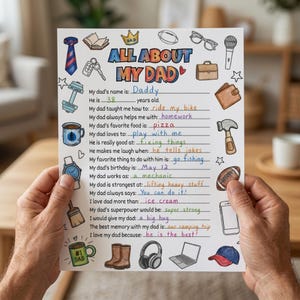 Pode incluir: Uma folha personalizada "Tudo sobre o meu pai", segurada por mãos. A folha apresenta ilustrações coloridas de uma gravata, ferramentas e uma caneca de café. O texto inclui perguntas sobre o nome, idade e preferências do pai.