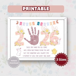 May include: A framed, printable Easter-themed artwork. The design features a handprint, the numbers "26", and the text "Happy Easter". Adorned with bunny ears, flowers, and a banner. Includes the text "These tiny hand you see today..." and "3 Sizes".