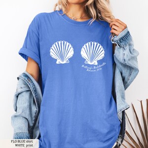 Puede incluir: Camiseta azul con dos dise&ntilde;os de conchas blancas. El texto "Brittany's Bachelorette Bahamas 2026" est&aacute; impreso debajo de las conchas. La camiseta es de color azul liso.