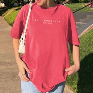 Minimalist Cool Aunts Club Est 2026 Comfort Colors shirt in dark neutral tone, modern aunt pregnancy announcement tee, trendy new aunt gift with clean typography aesthetic