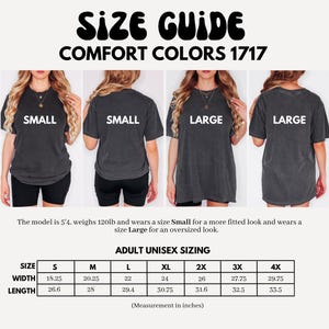 Op de afbeelding: Maattabel voor Comfort Colors 1717 t-shirts. De afbeelding toont modellen die kleine en grote shirts dragen. De maattabel geeft afmetingen in inches, wat overeenkomt met breedtes van 46,35 cm tot 75,57 cm en lengtes van 67,56 cm tot 85,09 cm.