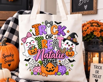 Può includere: Una borsa in tela bianca con una grafica colorata di Halloween e il testo "TRICK OR TREAT Natalie". Il design include due fantasmi dei cartoni animati, una zucca, ragnatele, pipistrelli e caramelle, decorati con fiocchi e motivi.