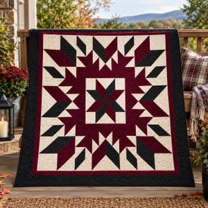May include: A rectangular quilt featuring a central star pattern in black and cream, surrounded by geometric shapes in deep burgundy, black, and cream. The quilt has a solid black border and intricate stitching throughout the fabric surface.