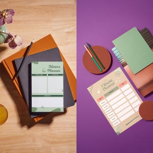 May include: Two fitness planners are displayed. One is on a wooden surface with a pencil and notebooks. The other is on a purple surface with a green notebook and pencils. Both planners have the text "Fitness Planner".