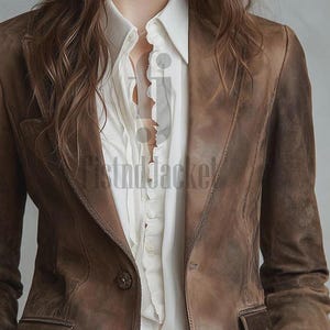 May include: A brown leather blazer with a classic design. The blazer features a notched lapel, two front pockets, and button closures. The blazer is worn over a white collared shirt.