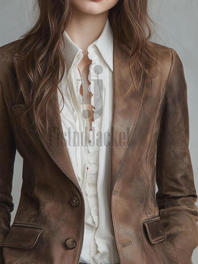May include: A brown leather blazer with a classic design. The blazer features a notched lapel, two front pockets, and button closures. The blazer is worn over a white collared shirt.
