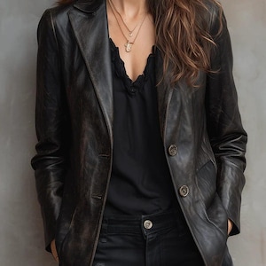 May include: A black leather blazer with a classic notched lapel and two button closure. The blazer has a slightly distressed appearance and is paired with a black top and black jeans. A gold necklace is visible.