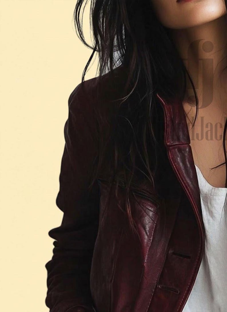 May include: A burgundy leather jacket with a classic button-up design. The jacket has a tailored fit and a rich, deep color. The image shows the jacket's shoulder and lapel details, suggesting a stylish outerwear piece.