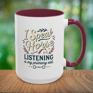 May include: White ceramic mug with a claret interior and handle. The mug features the text "I Speak Horse Listening is my primary aid." in a decorative font, with a horse graphic.