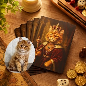 May include: A rectangular card featuring a digital illustration of an orange tabby cat dressed as a monarch in a red velvet robe, gold crown, and ornate jewelry, layered over a circular photograph of a fluffy orange kitten sitting on a textured surface.