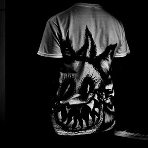 K&ouml;nnte beinhalten: Hellgraues T-Shirt mit einer schwarz-wei&szlig;en Grafik eines Monstergesichts. Das Design umfasst gro&szlig;e Augen, spitze Z&auml;hne und spitze H&ouml;rner. Die Grafik ist auf der R&uuml;ckseite des T-Shirts aufgedruckt.