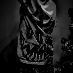 K&ouml;nnte beinhalten: Schwarz-wei&szlig; gemusterter Stoff mit einem gro&szlig;en, stilisierten Design. Der Stoff ist drapiert, mit sichtbaren Falten und Schatten. Im Hintergrund ist ein Weihnachtsbaum zu sehen.