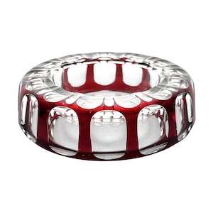 May include: A clear glass ashtray with a red rim and intricate cut-out design.