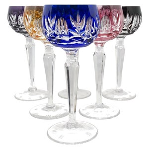 Może przedstawiać: Zestaw sześciu kryształowych kieliszków do wina z wzorami z ciętego szkła. Kieliszki są przezroczyste z kolorowymi podstawami w kolorze fioletowym, złotym, niebieskim, różowym i czarnym.